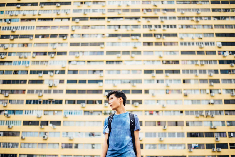 man standing in front of a block of flats