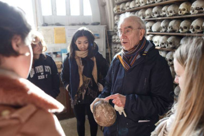 Expert showing ancient human skull from ossuary collection to students