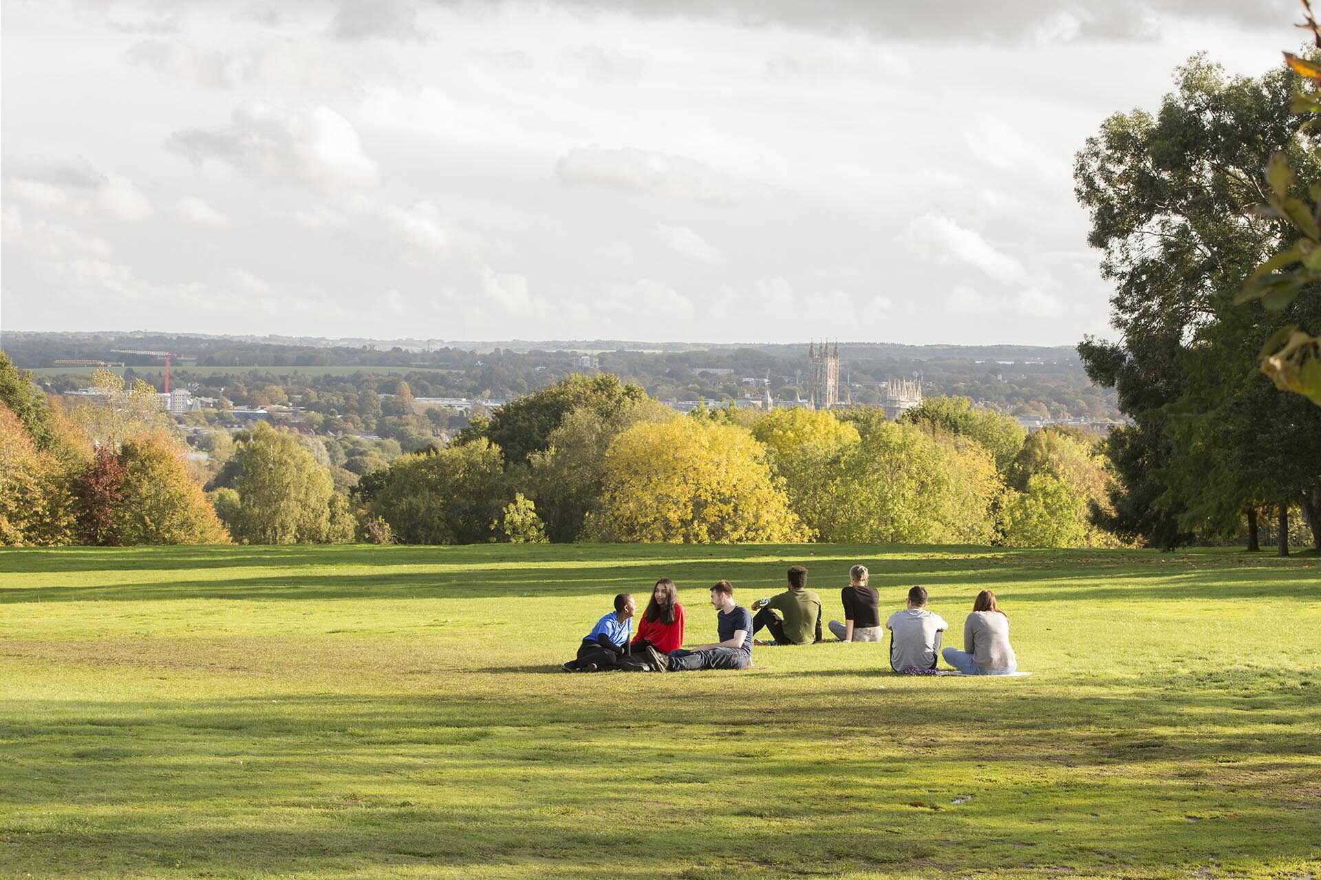 Students sit on the grass overlooking Canterbury