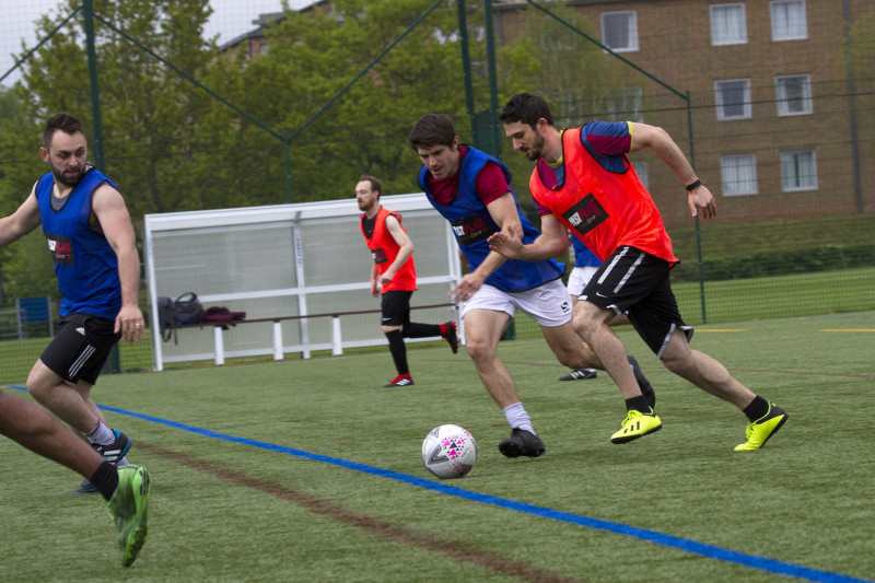 Two men on opposite teams chasing the ball during a game of football
