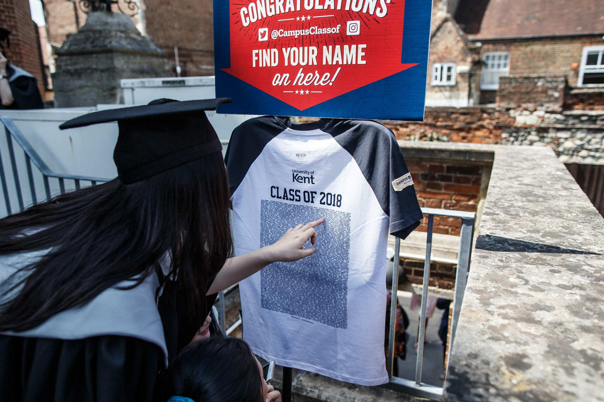 A graduand looking at a 'Class of 2018' t-shirt for their name.