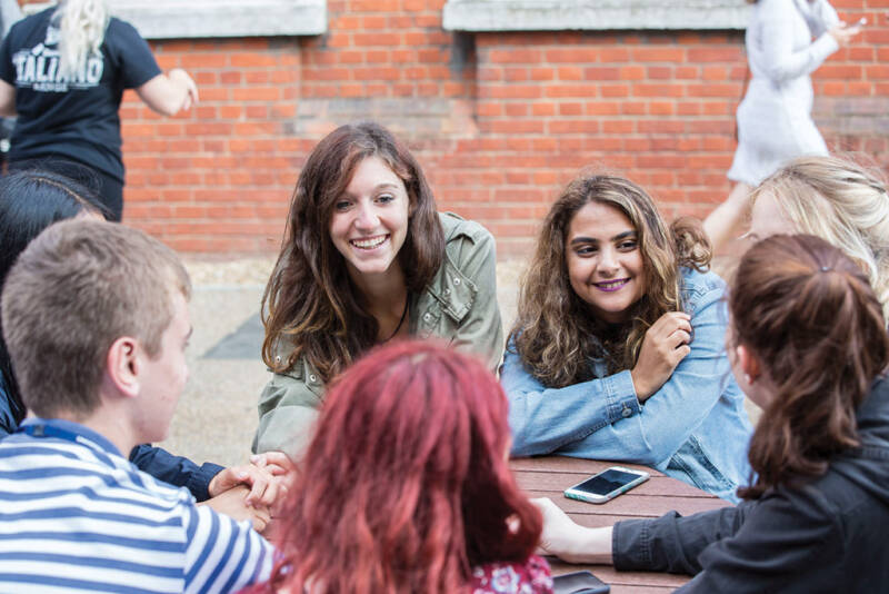 A group of students sat talking around a table outside at the Medway campus.