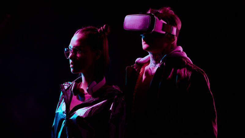 two figures, one wears a VR headset