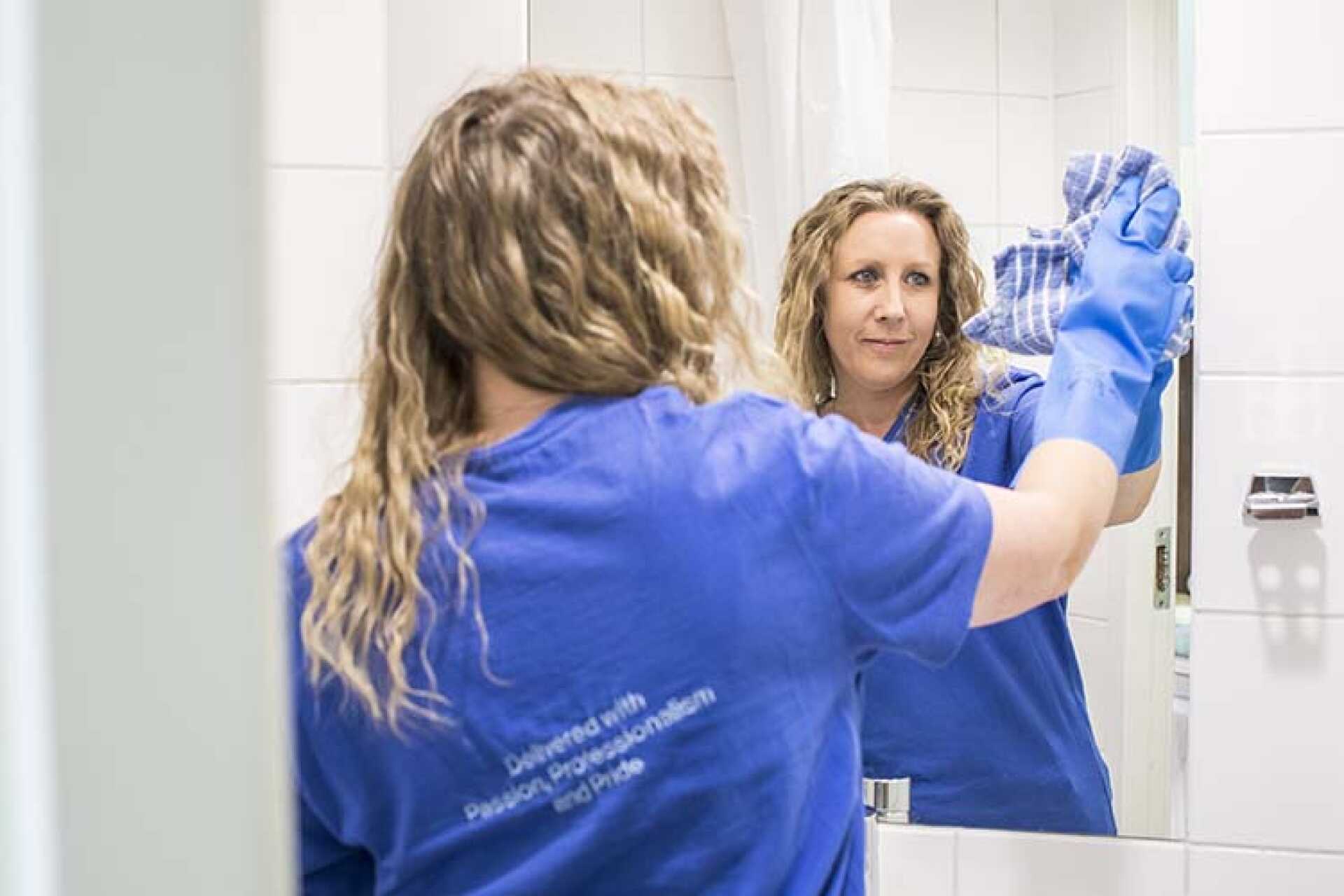 Housekeeper cleaning mirror