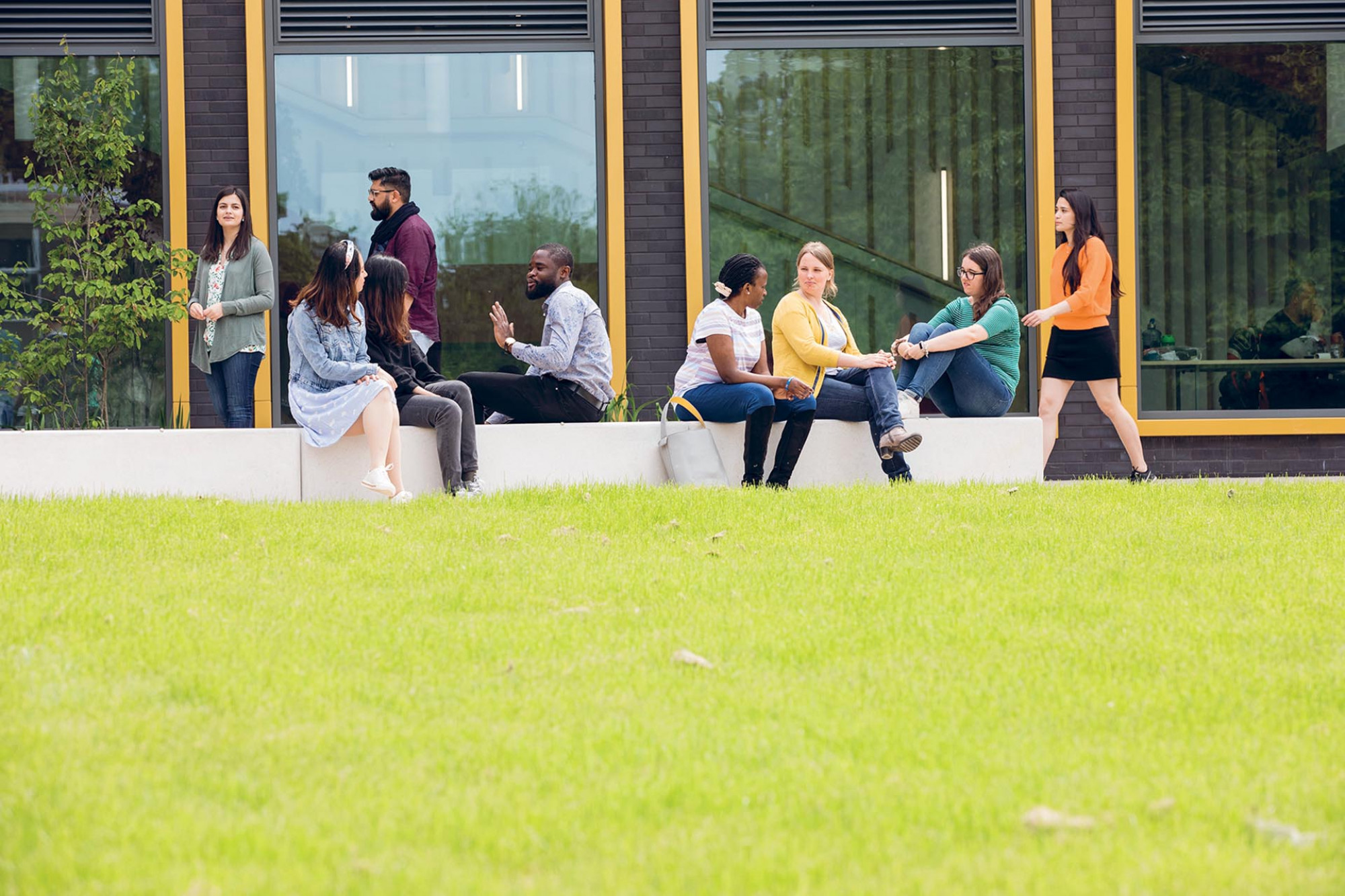 A group of postgraduates sit outside the Kennedy Building on the Canterbury campus