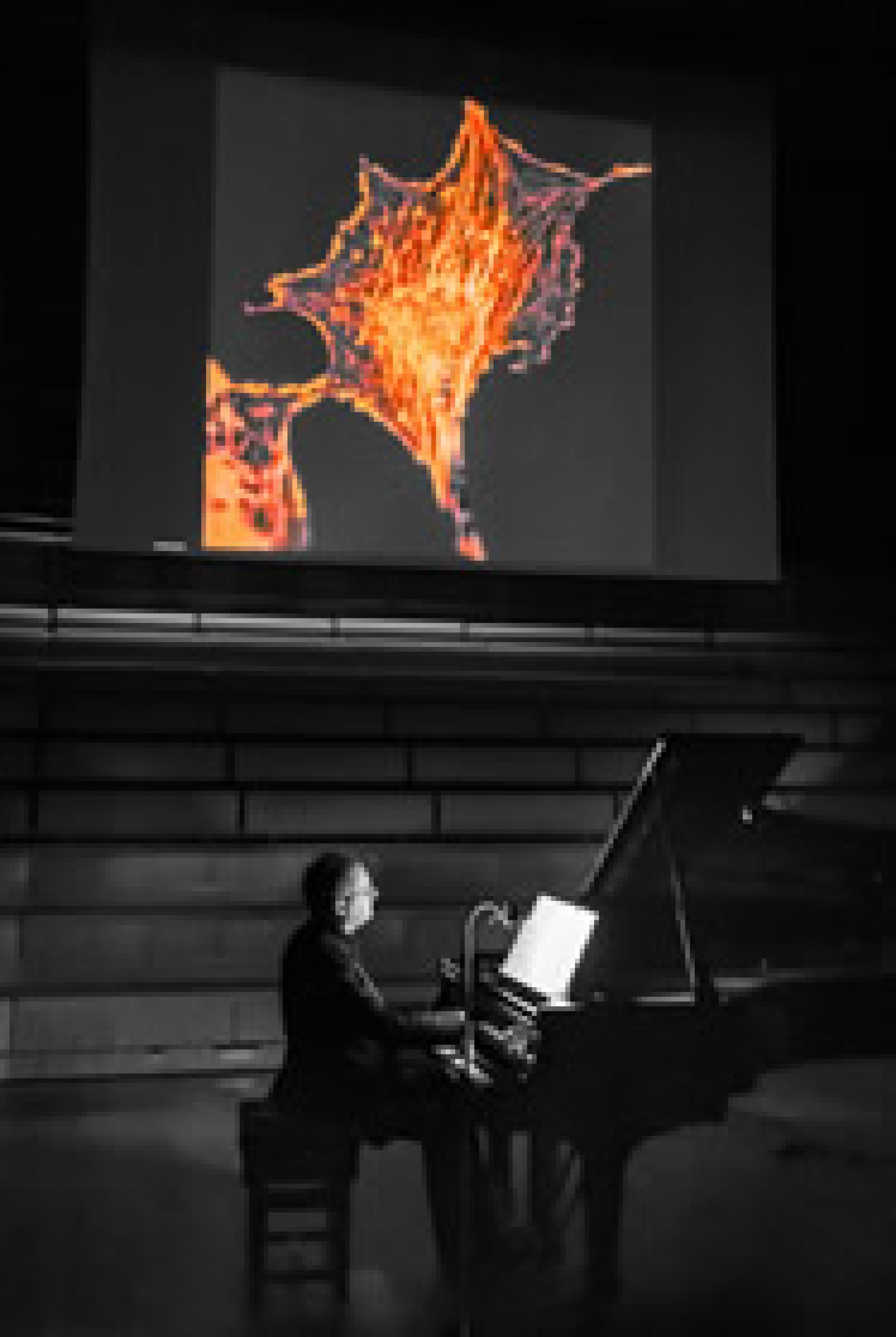 Pianist playing beneath a projector screen in the concert-hall