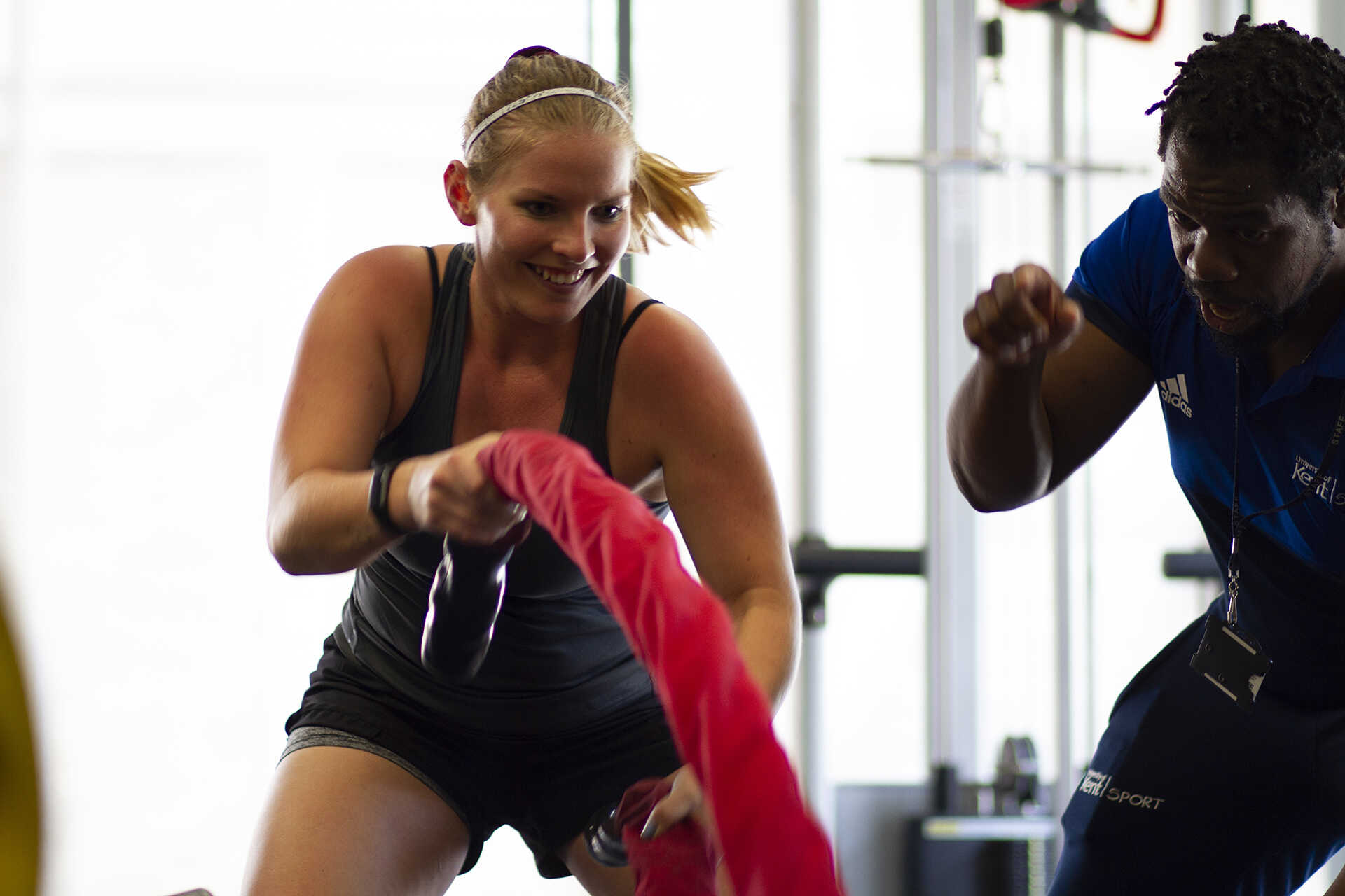 Woman smiling and swinging battle ropes during a personal training session