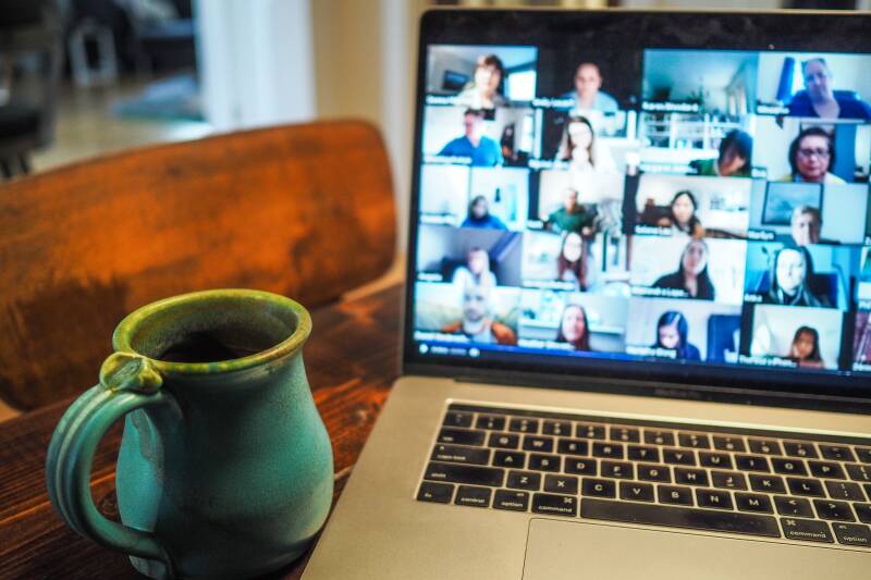 Zoom meeting on a laptop with a coffee mug in the foreground