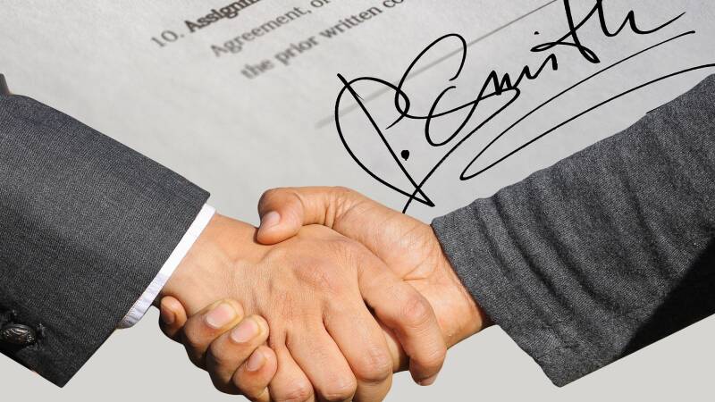 A handshake with signatures in the background
