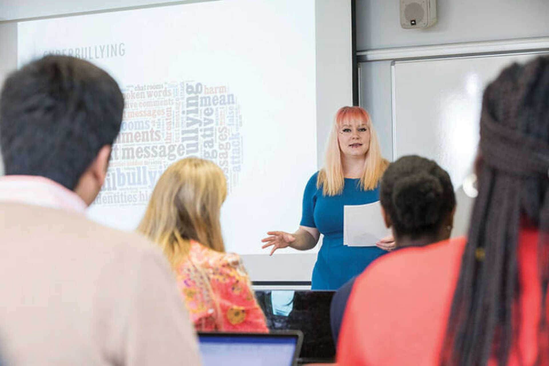 Lecturer in front of a screen teaching students