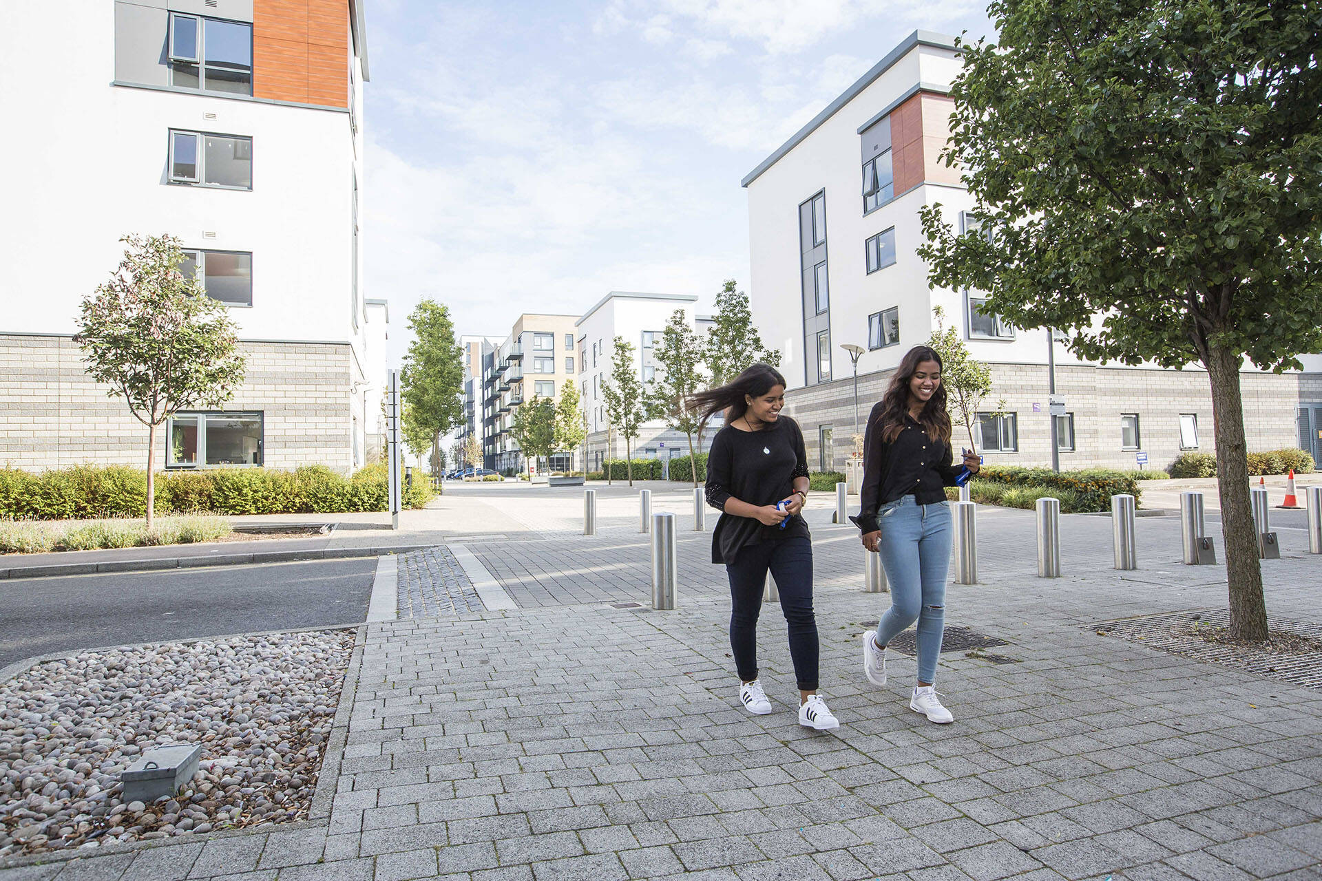 Two students smiling and laughing walking through Pier Quays