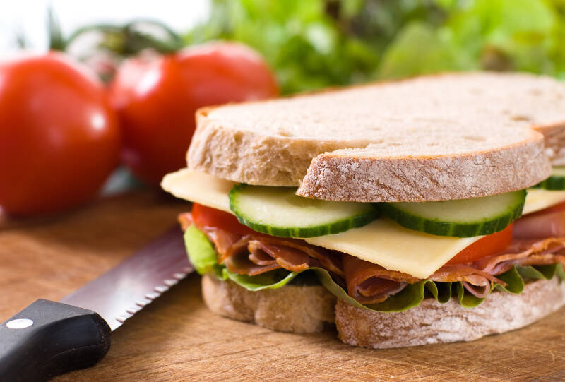 A bacon and salad sandwich on a chopping board