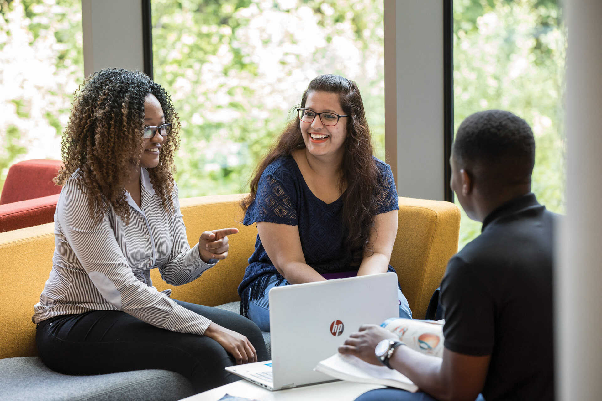 Three students talking on sofas