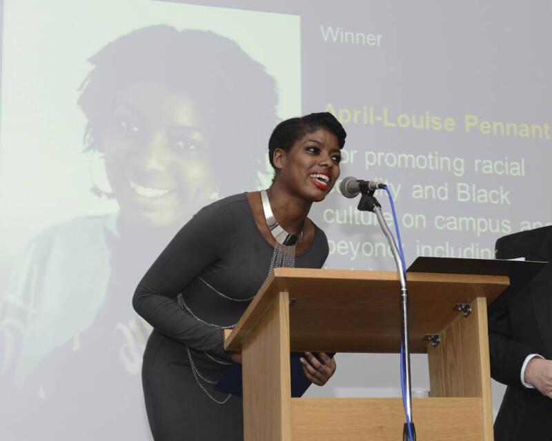 A student accepting an award in front of a screen which says 'Promoting racial equality and Black culture on campus'.