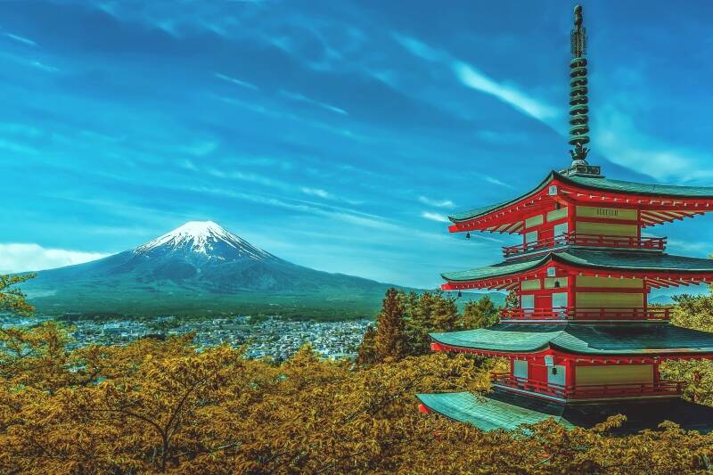 A red pagoda with Mount Fuji visible in the background against a blue sky