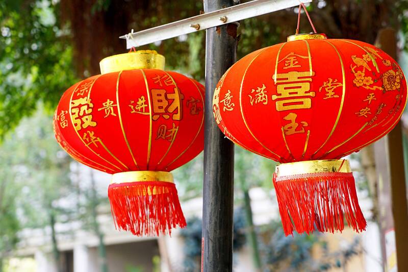Two red and gold Chinese New Year lanterns hanging, blowing slightly in the breeze