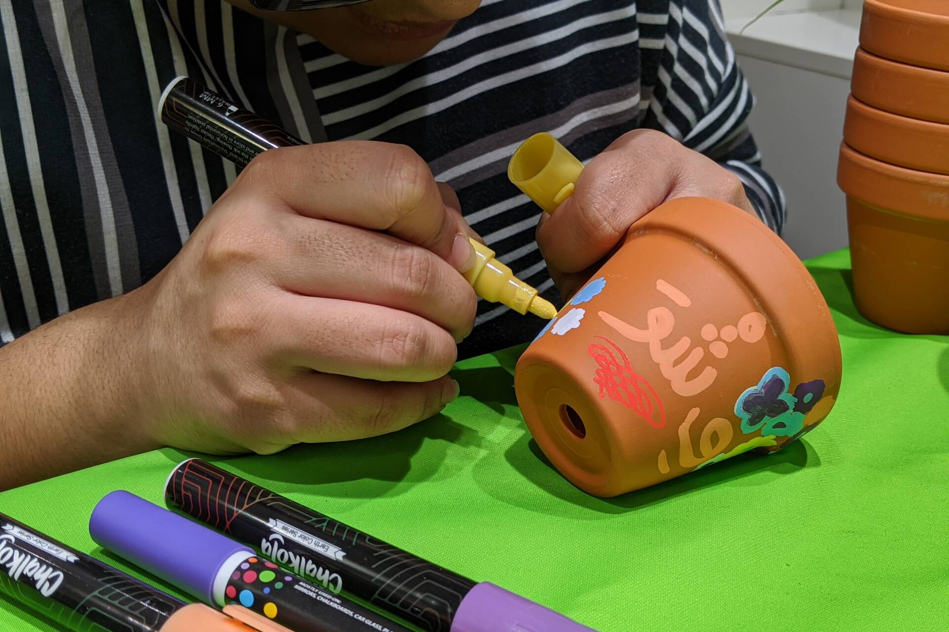 A student drawing on a terracotta pot against a green tablecloth
