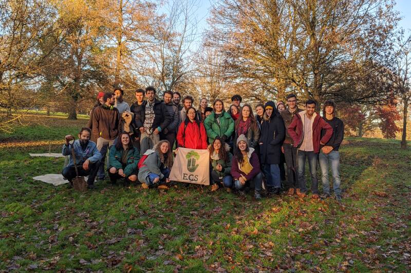 Environmental Conservation Society gathered on a field holding a ecs sign