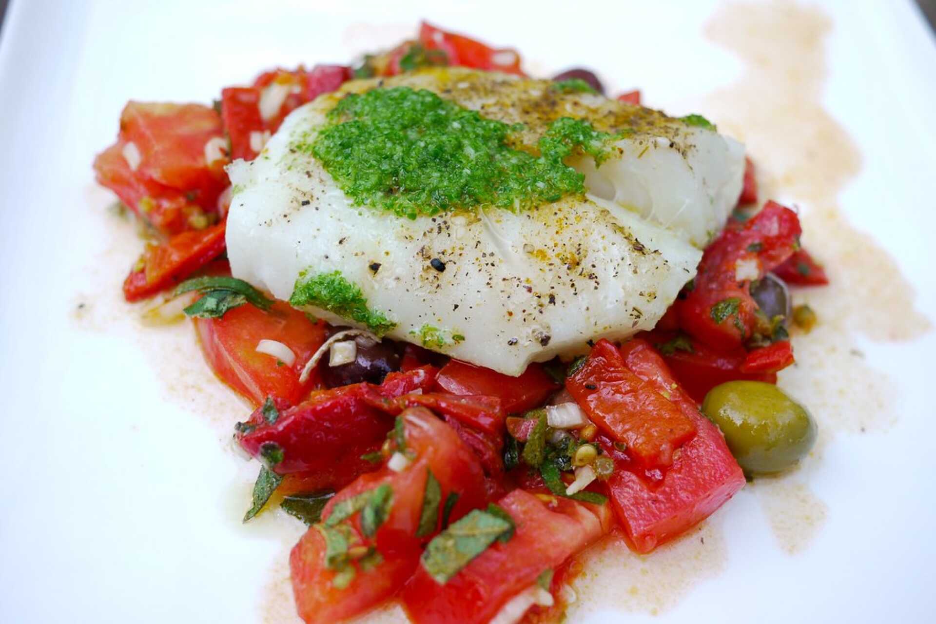 Cooked white fish on top of Mediterranean vegetables