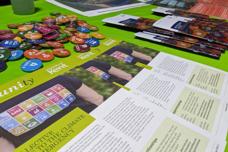 A green table with leaflets and badges arranged on it.