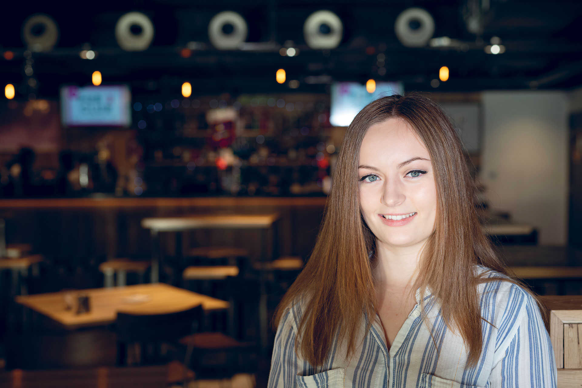 Female student sitting at a table in a bar