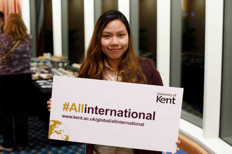 Kent Alumni student holding up #allinternatinal sign