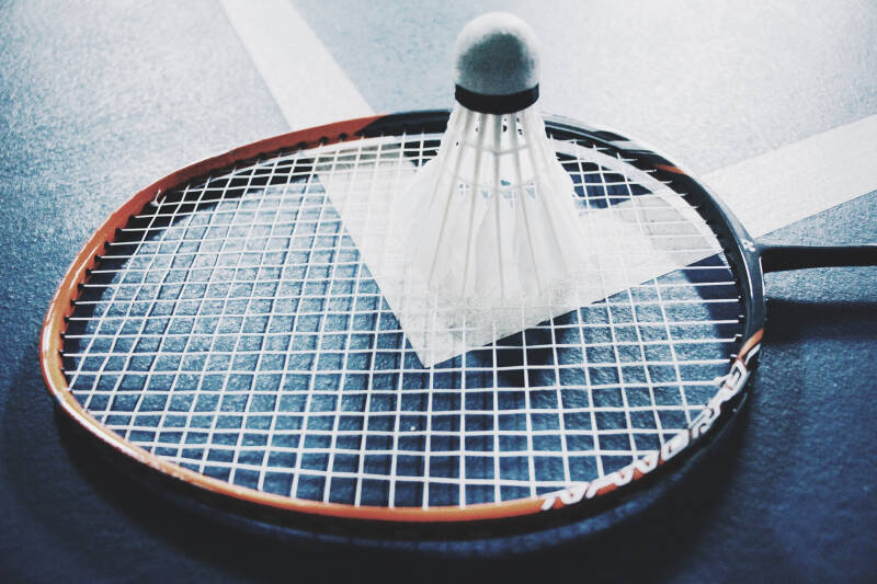 Close-up of a badminton racket on the floor with shuttlecock placed on facing upwards