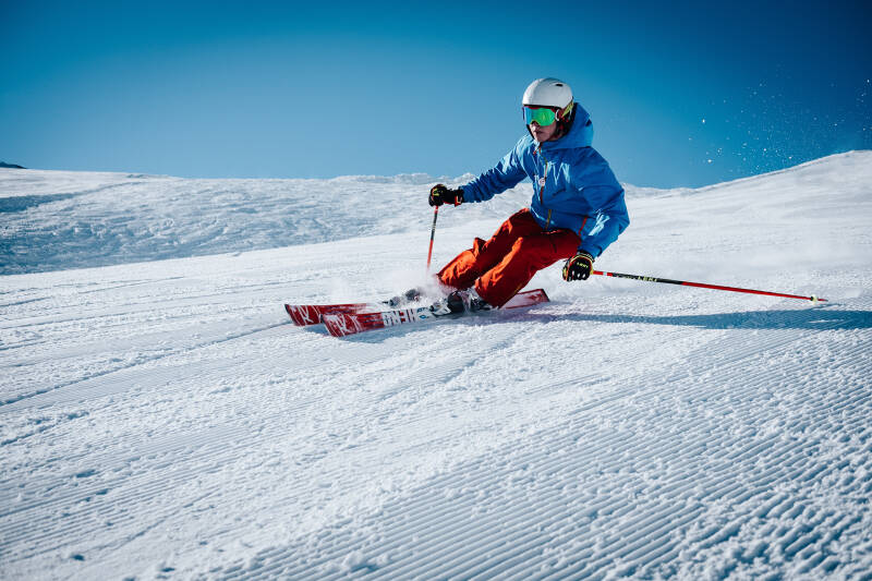 Person skiing on snow on bright day with blue sky