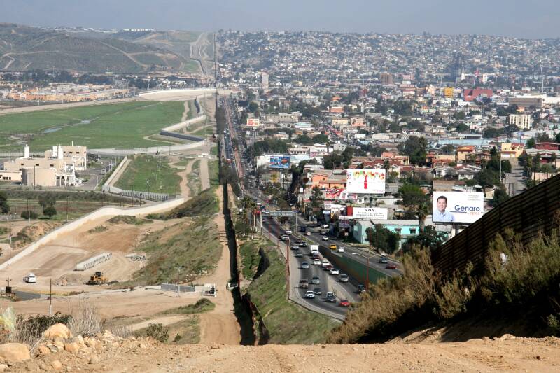 The US-Mexico border cuts vertically across the image. The crowded US side on the right and open space of Mexico on the left
