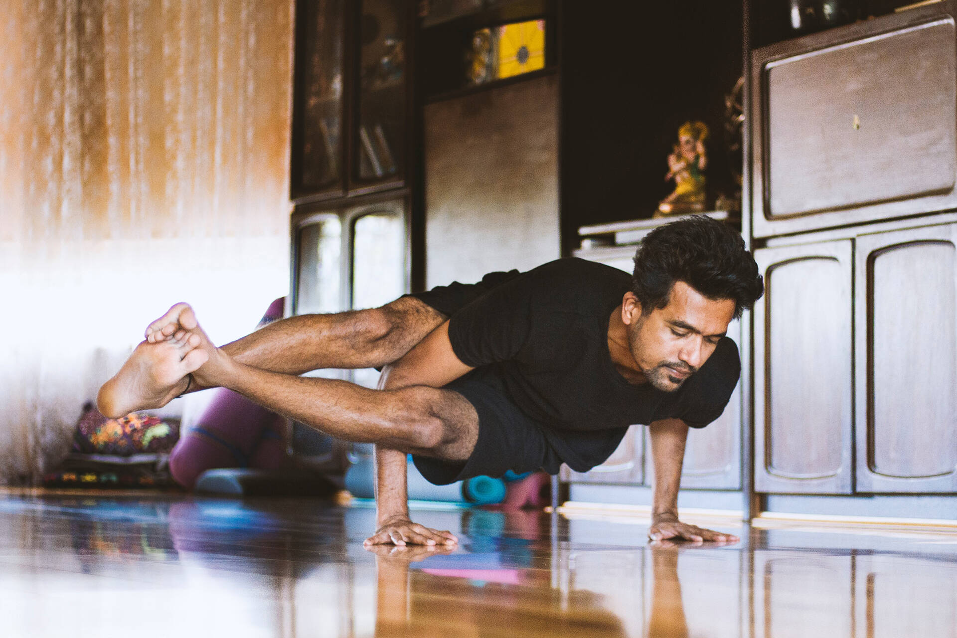 Man practising yoga pose on the floor in his house