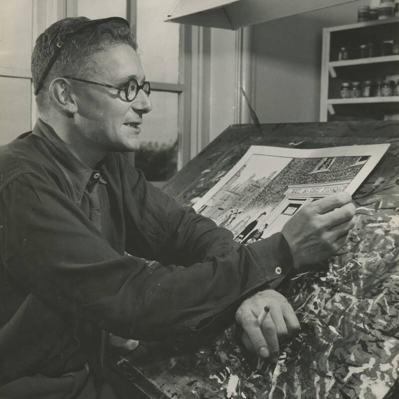 GAPH00450: Black and white photo of close up of Giles at his easel; finished artwork on easel, 1946.
