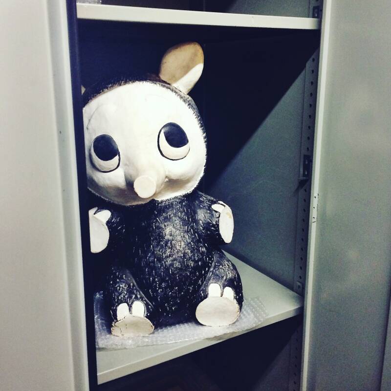 A photograph of a large papermache model of Trog's character, Flook, sitting in a large maetal cabinet.