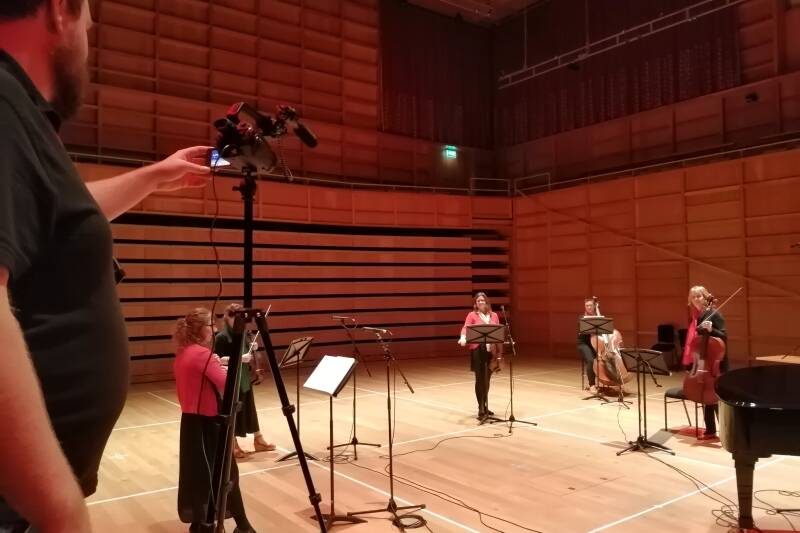Cameraman filming the string players in rehearsal in the concert-hall