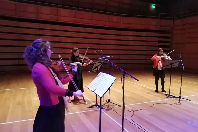 Three string players playing in a darkened concert-hall