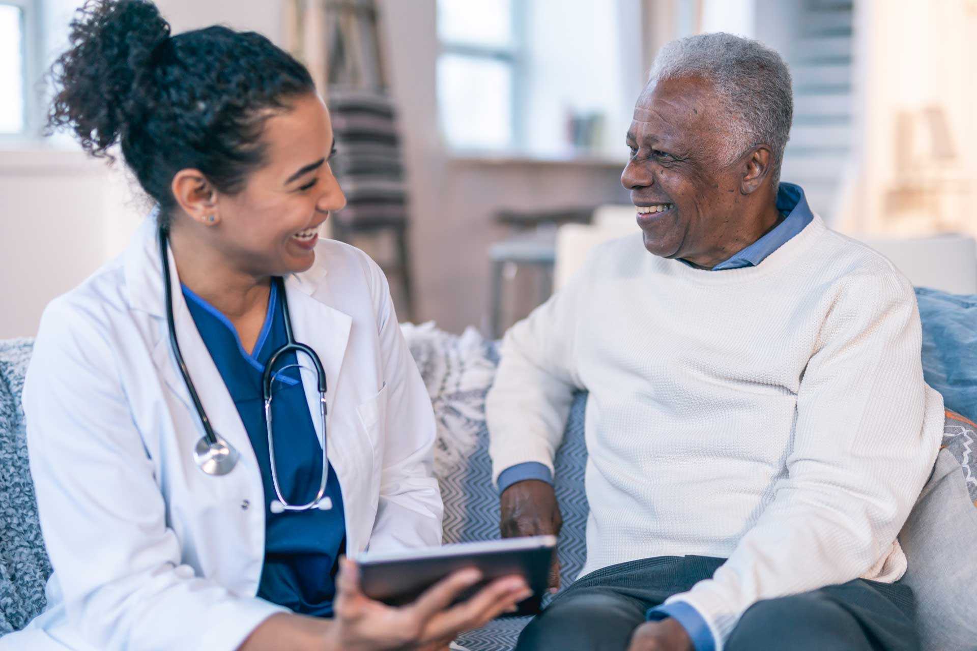 Smiling young female doctor talking with smiling older male patient