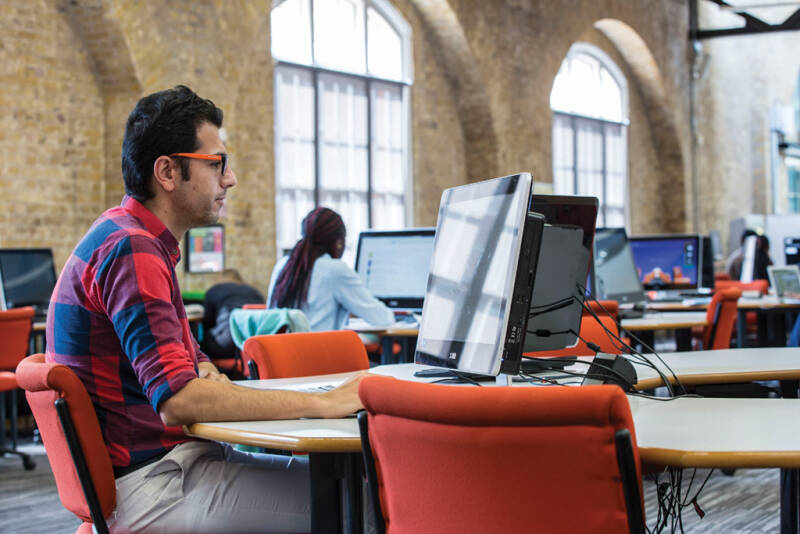 A man using a computer in Drill Hall library.