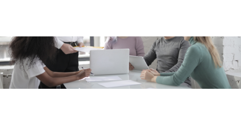 Focus on a laptop with 5 people sitting and standing around it.