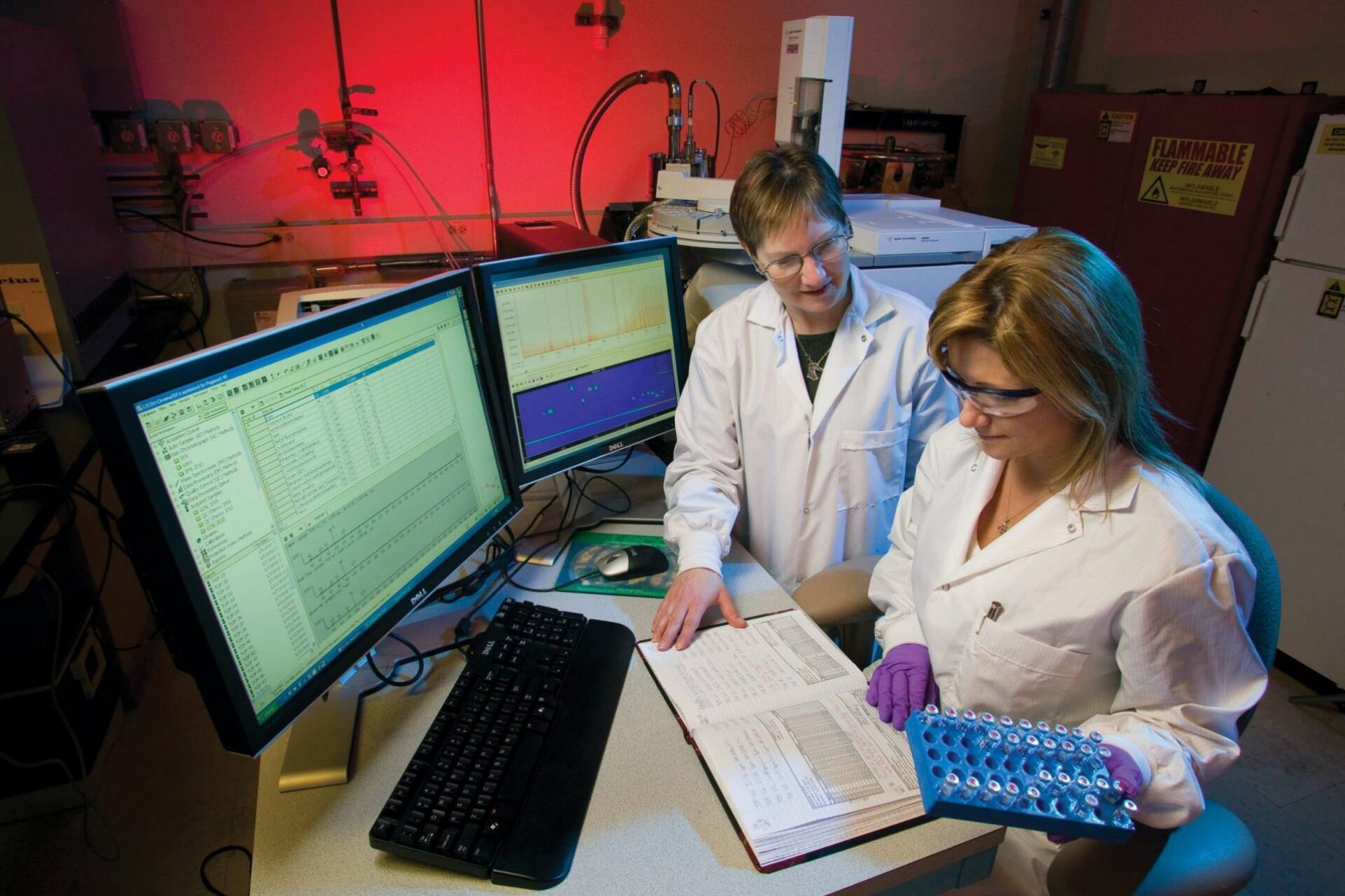 Two ladies in lab coats analysing data on a screen