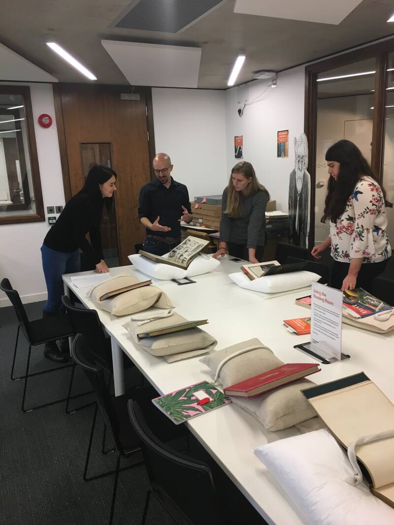 A group of students looking at a Victorian journal as their teacher explains the item.