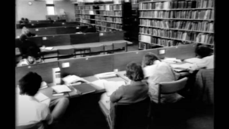 Still of people studying in the library in 1981
