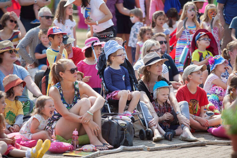 Families and children in audience watching an outdoor performance