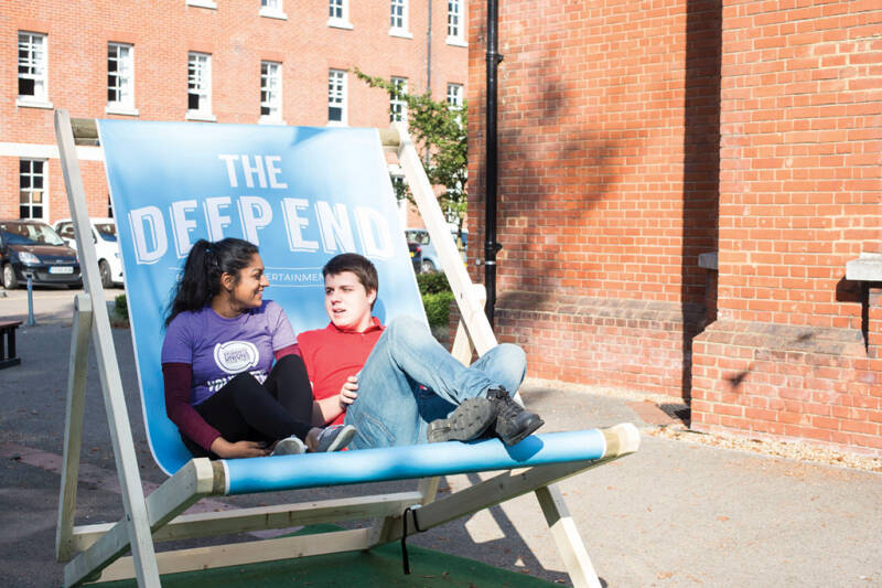 Two students sit on deckchair outside Medway campus