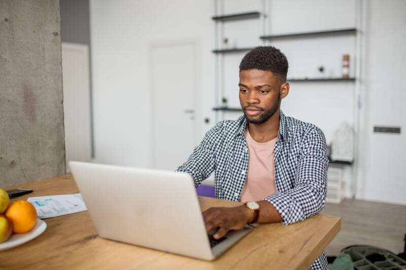 Male student working at laptop in kitchen