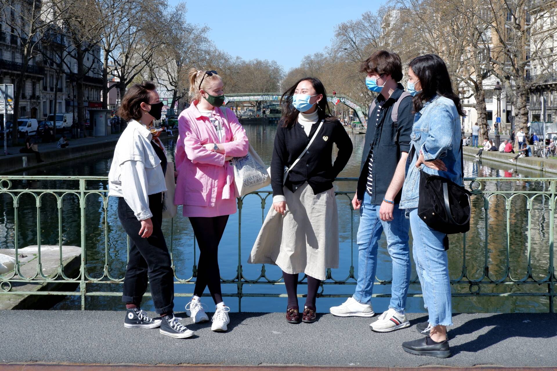 Young adults standing on a bridge above a river in Paris