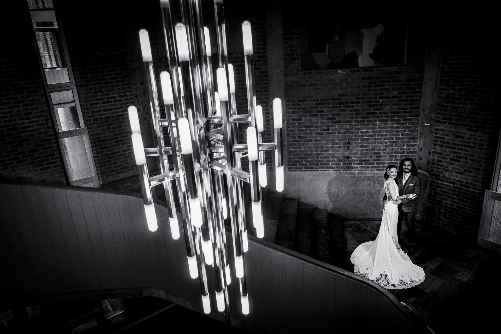 Bride and Groom standing on the stairs, looking across and up at the camera