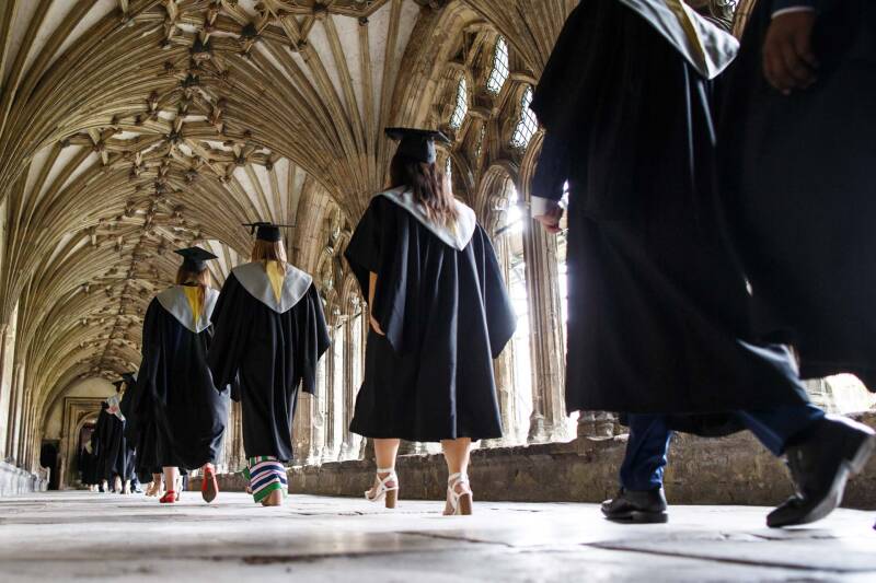 Graduands walking through Canterbury Cathedral cloisters