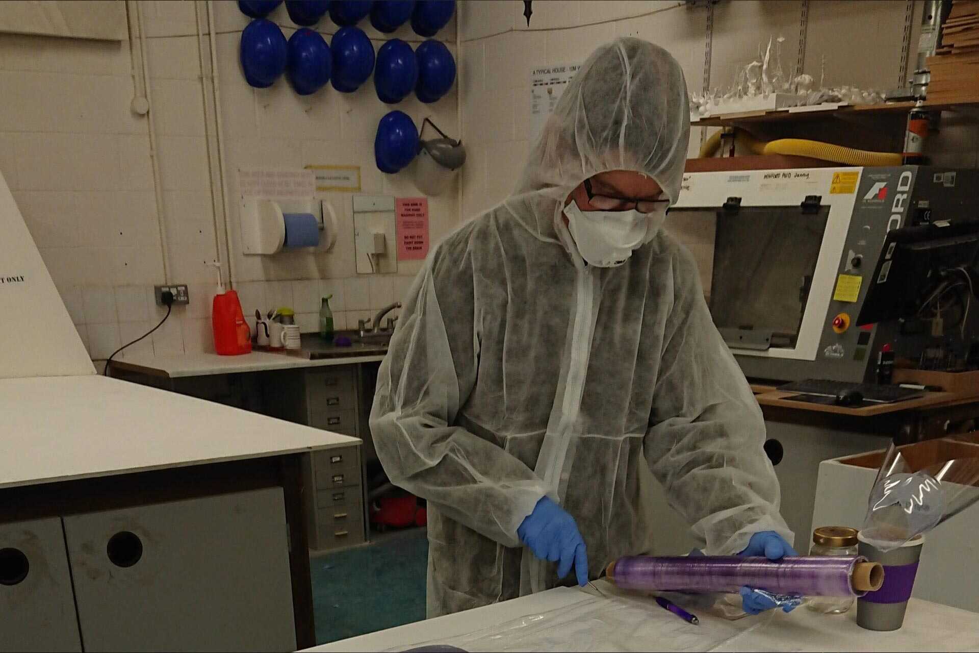 Person making face shield, while wearing PPE