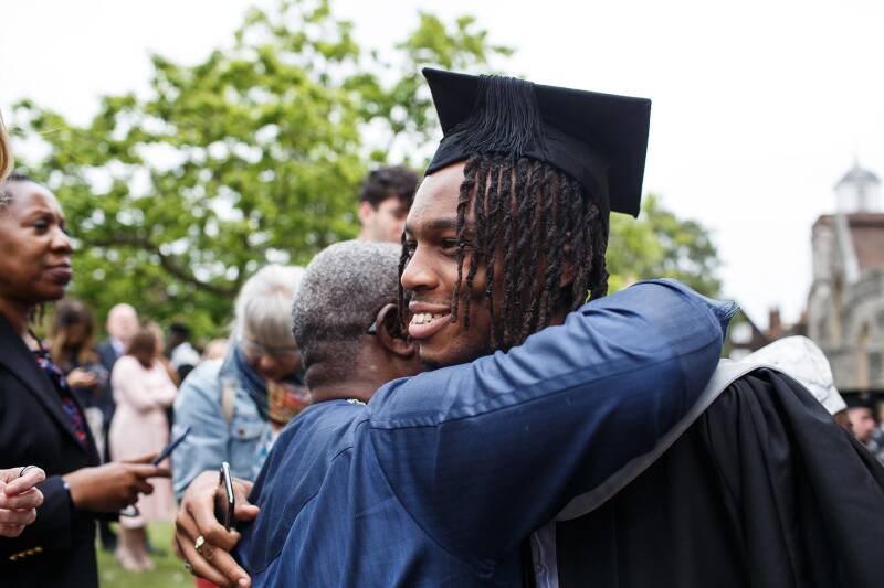 Emmanuel Enemokwu hugging a guest after his graduation ceremony