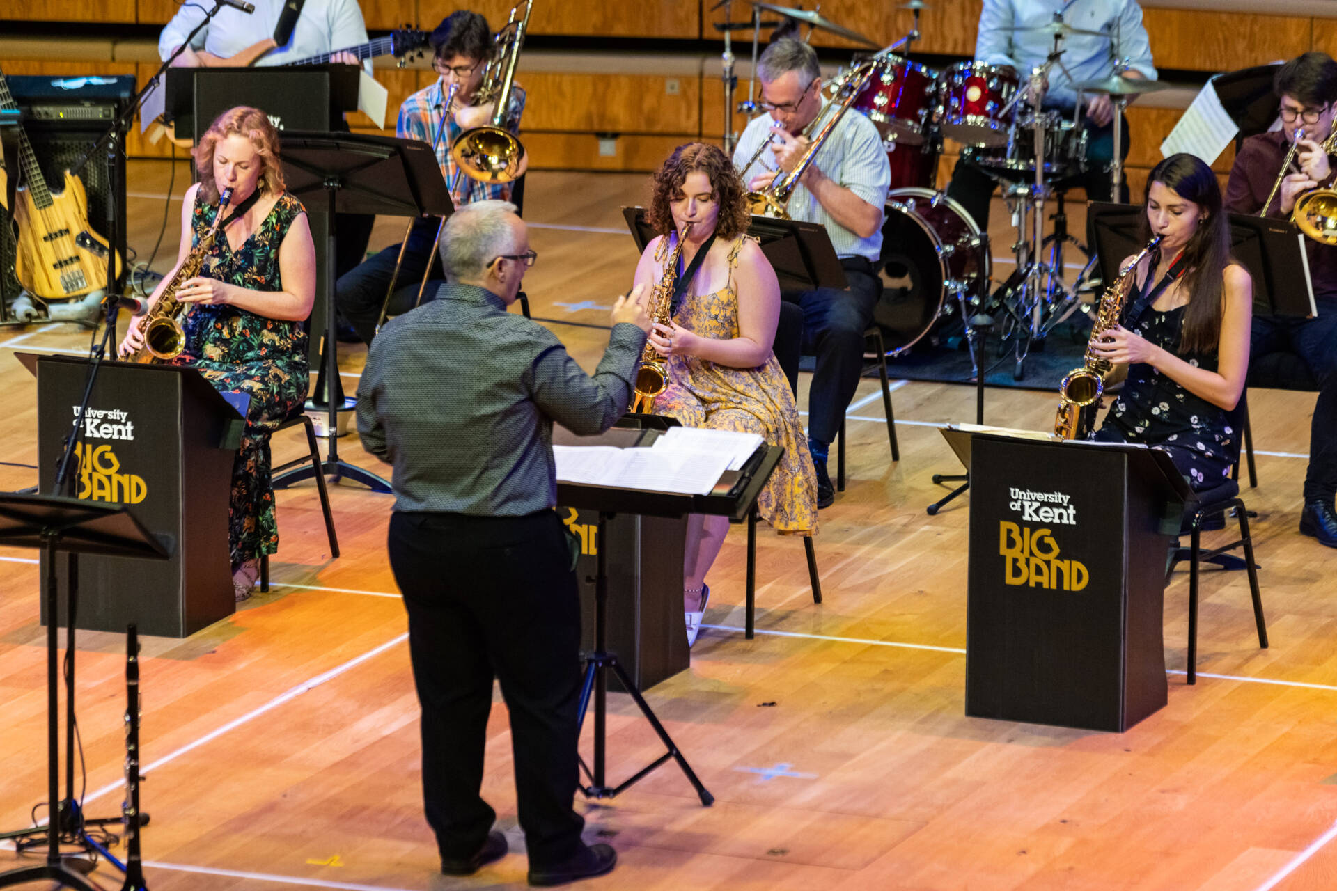Jazz musicians playing on-stage in front of a conductor