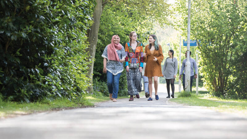 A group of female students in colourful dress walking onto campus.